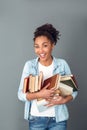 Young african woman isolated on grey wall studio casual daily lifestyle standing with books playful