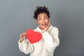 Young african woman on grey wall studio winter concept holding heart dreaming Royalty Free Stock Photo