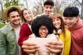 Young African girl taking a selfie portrait of her large group of friends hugging and smiling. Royalty Free Stock Photo