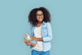 Freestyle. African girl student wearing glasses standing isolated on gray with books looking aside joyful Royalty Free Stock Photo