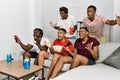 Young african group of friends sitting on the sofa at home playing video games celebrating victory with happy smile and winner Royalty Free Stock Photo
