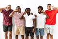 Young african group of friends standing together over isolated background doing peace symbol with fingers over face, smiling Royalty Free Stock Photo