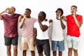 Young african group of friends standing together over isolated background shouting and screaming loud to side with hand on mouth Royalty Free Stock Photo