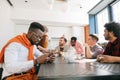 Young african guy with mobile phone ignoring his co-workers birthday