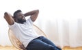 Young african guy relaxing at home, resting on chair