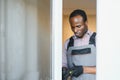 Young African Handyman In Uniform Fixing Glass Window With Screwdriver Royalty Free Stock Photo