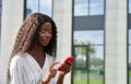 Young African woman model using mobile cell phone standing outdoors. Royalty Free Stock Photo