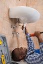 Plumber Lying On Floor Fixing Sink In Bathroom Royalty Free Stock Photo