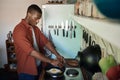 Young African man cracking eggs into a frying pan
