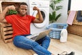 Young african man doing laundry and using computer showing arms muscles smiling proud Royalty Free Stock Photo