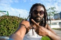 young African man with dreadlocks and beard sitting looking at camera making v sign with hand Royalty Free Stock Photo