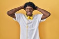 Young african man with dreadlocks standing over yellow background crazy and scared with hands on head, afraid and surprised of Royalty Free Stock Photo