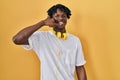 Young african man with dreadlocks standing over yellow background smiling doing phone gesture with hand and fingers like talking Royalty Free Stock Photo