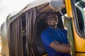 young african man driving a tuk tuk taxi smiling on a very sunny day Royalty Free Stock Photo