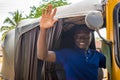 young african man driving a tuk tuk taxi smiling on a very sunny day waving to a passenger Royalty Free Stock Photo
