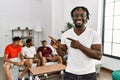 Young african man with friends at the living room smiling and looking at the camera pointing with two hands and fingers to the Royalty Free Stock Photo