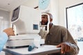 Young African man getting an eye exam by an optometrist with technical optic equipment. Male getting an eyesight test Royalty Free Stock Photo