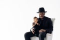 Young african man in hat sits in armchair with his baby daughter from interracial marriage