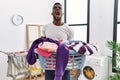 Young african man holding laundry basket angry and mad screaming frustrated and furious, shouting with anger looking up Royalty Free Stock Photo