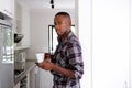 Young african man in the kitchen with mobile phone and coffee Royalty Free Stock Photo