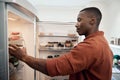 Young African man looking for something in his refrigerator Royalty Free Stock Photo