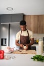 Young african man peeling onion to prepare chicken recipe.