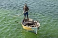 A young african man pilots a simple wooden boat.