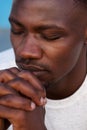 Young african man praying with hands clasped and eyes closed Royalty Free Stock Photo