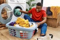 Young african man putting dirty clothes into washing machine at laundry room Royalty Free Stock Photo