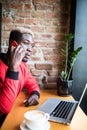 Young African man sitting at the coffee shop talk mobile phone. Student wearing trendy clothes, drinking coffee, using wireless In Royalty Free Stock Photo