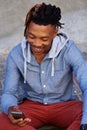 Young african man sitting outside with mobile phone Royalty Free Stock Photo