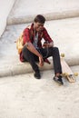 Young african man sitting outside on steps and listening to music Royalty Free Stock Photo