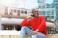 Young african man sitting outside using mobile phone Royalty Free Stock Photo