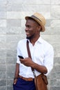 Young african man smiling against gray wall with mobile phone Royalty Free Stock Photo