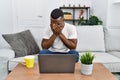 Young african man using laptop at home with sad expression covering face with hands while crying Royalty Free Stock Photo