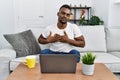 Young african man using laptop at home smiling with hands on chest with closed eyes and grateful gesture on face Royalty Free Stock Photo