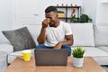 Young african man using laptop at home tired rubbing nose and eyes feeling fatigue and headache Royalty Free Stock Photo