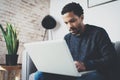 Young African man using laptop while sitting sofa at his modern coworking studio.Concept of full concentration.Blurred Royalty Free Stock Photo