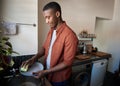 Young African man washing dishes in his kitchen at home Royalty Free Stock Photo