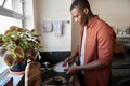 Young African man washing dishes in his kitchen sink at home Royalty Free Stock Photo