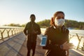 Young african man and woman in medical masks running on the bridge during a pandemic. Sport and coronavirus Royalty Free Stock Photo