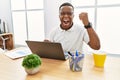 Young african man working at the office using computer laptop angry and mad raising fist frustrated and furious while shouting Royalty Free Stock Photo