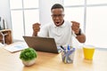 Young african man working at the office using computer laptop angry and mad raising fists frustrated and furious while shouting Royalty Free Stock Photo