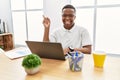 Young african man working at the office using computer laptop with a big smile on face, pointing with hand finger to the side Royalty Free Stock Photo