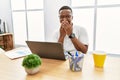 Young african man working at the office using computer laptop laughing and embarrassed giggle covering mouth with hands, gossip Royalty Free Stock Photo