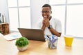 Young african man working at the office using computer laptop laughing nervous and excited with hands on chin looking to the side Royalty Free Stock Photo
