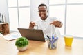 Young african man working at the office using computer laptop pointing to you and the camera with fingers, smiling positive and Royalty Free Stock Photo