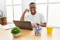 Young african man working at the office using computer laptop smiling doing phone gesture with hand and fingers like talking on Royalty Free Stock Photo