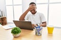 Young african man working at the office using computer laptop smiling and laughing with hand on face covering eyes for surprise Royalty Free Stock Photo