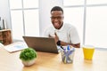 Young african man working at the office using computer laptop smiling and laughing hard out loud because funny crazy joke with Royalty Free Stock Photo